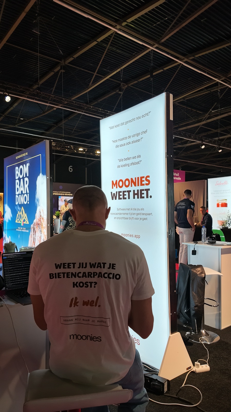 Behind the laptop at the moonies stand, wearing a shirt that reads: do you know what your beet carpaccio costs? I do.