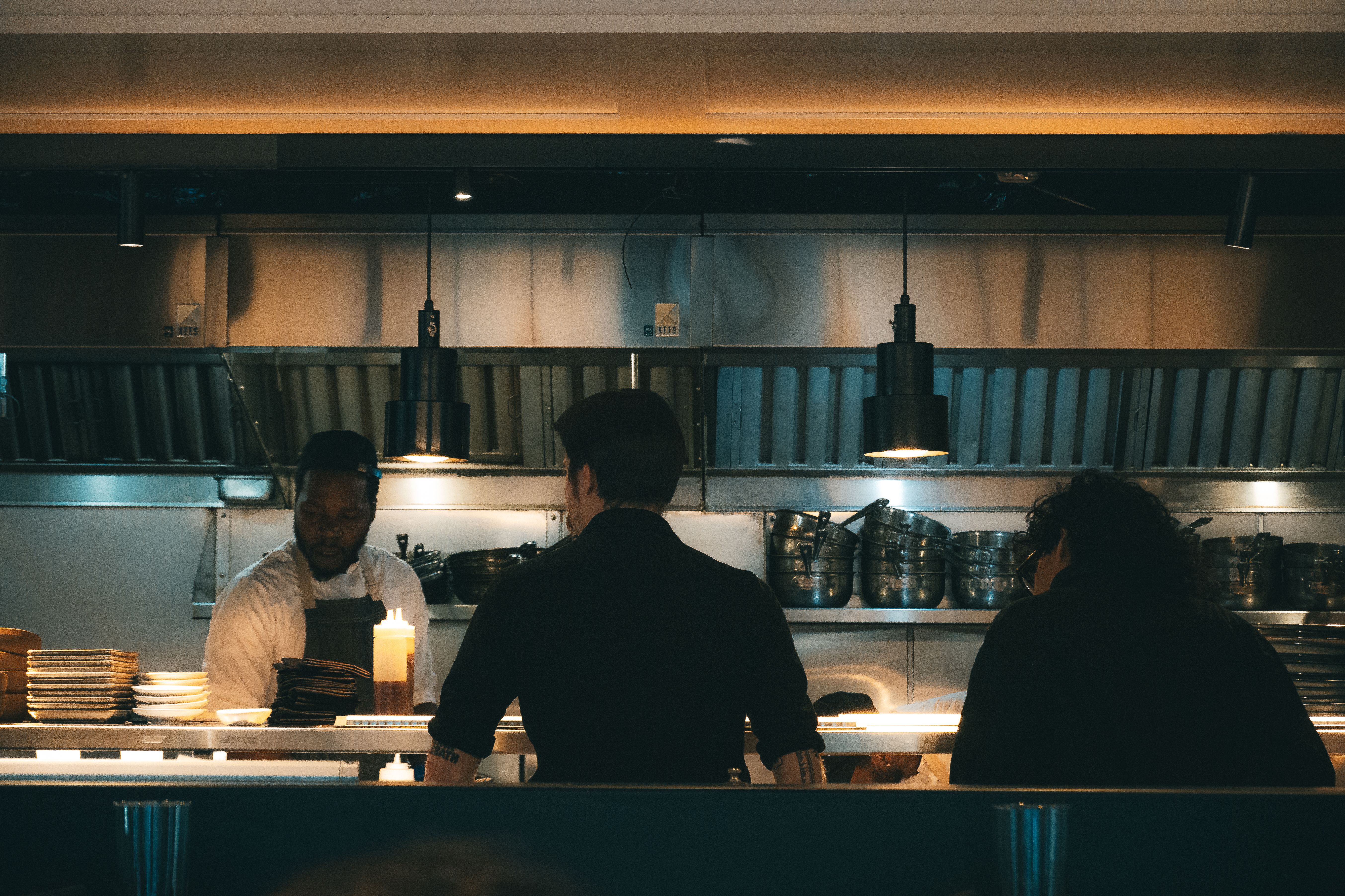 Kitchen staff at work behind the pass in a warmly lit kitchen, the work guests never see.